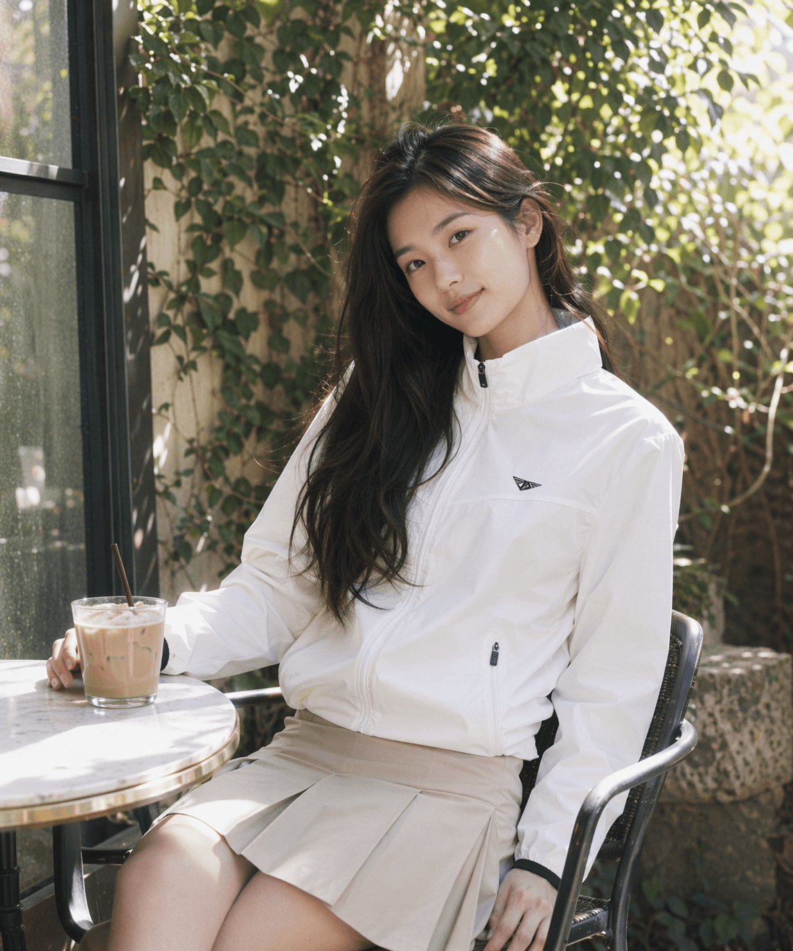 White windbreaker jacket worn with a skirt on a cafe street in spring
