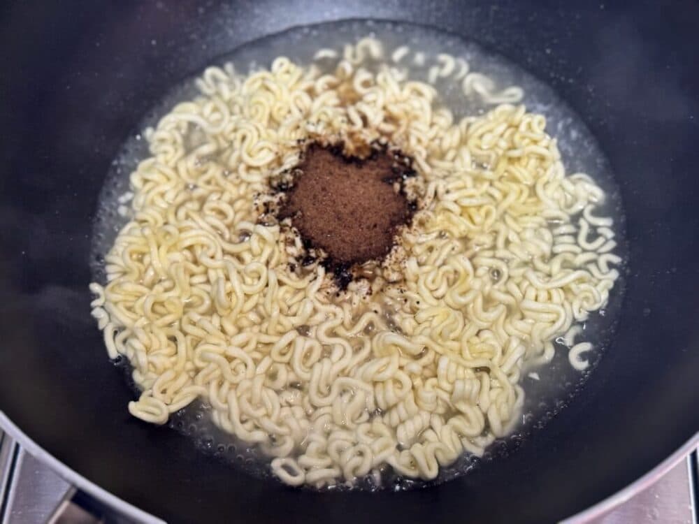 Chapagetti noodles with powdered seasoning added in the pan.